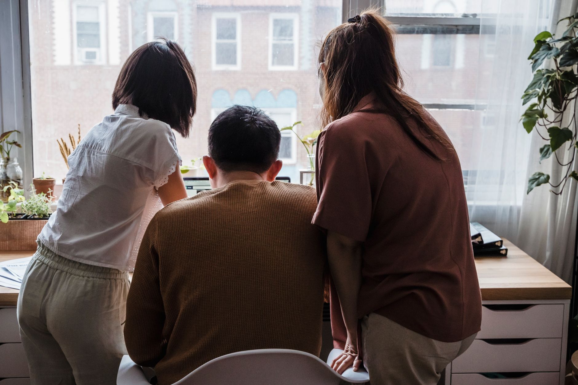 A small team collaborating at a desk in a sunlit office